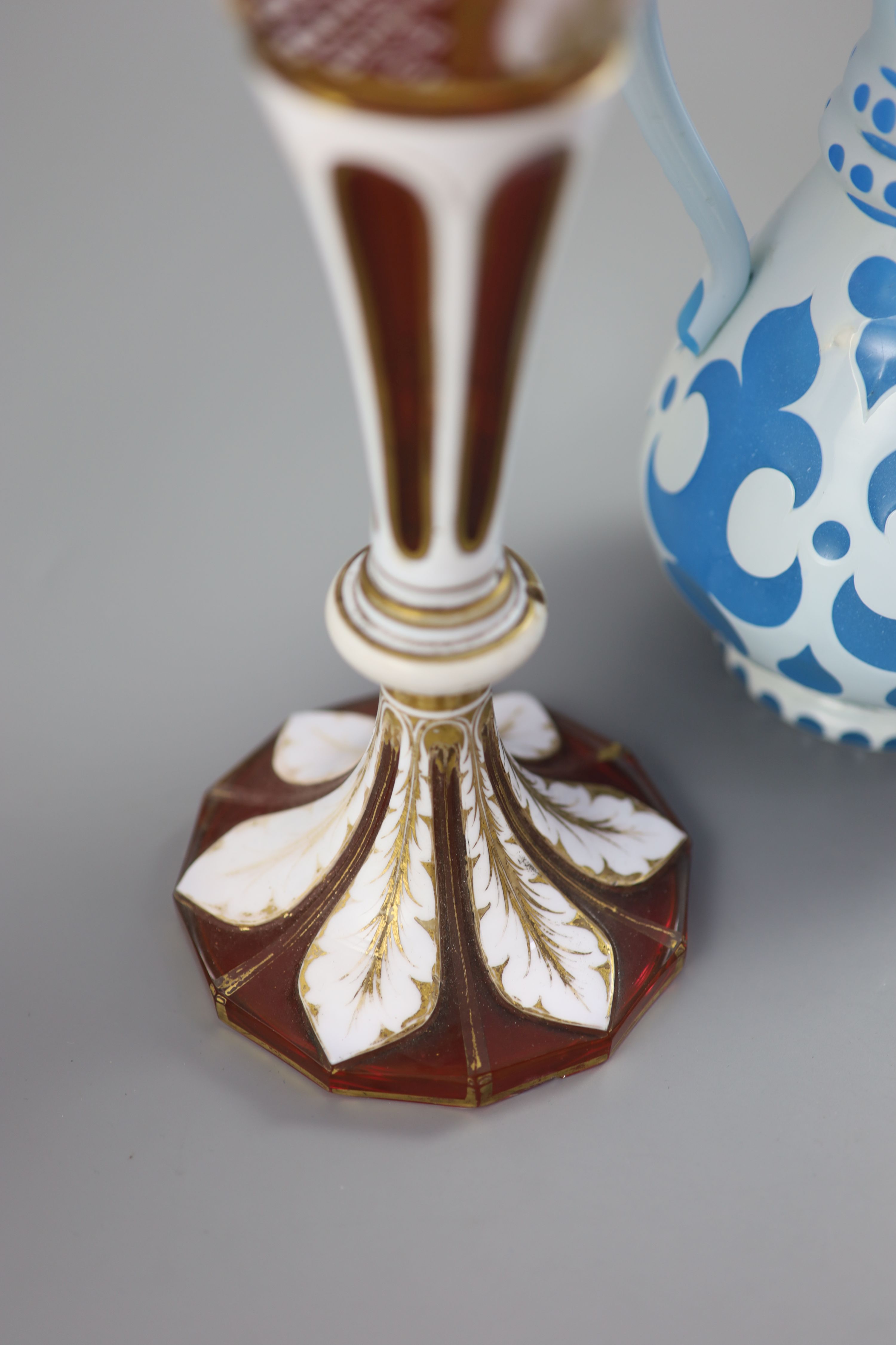 A Bohemian blue and white overlaid glass jug and a similar ruby and white overlaid glass vase, tallest 35cm